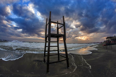 Lifeguard hut on beach against sky during sunset