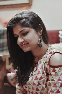 Smiling young woman in traditional clothing sitting at home