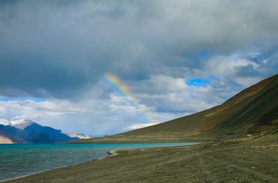 Scenic view of rainbow over sea against sky