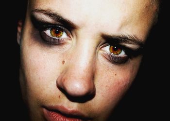 Close-up portrait of woman against black background