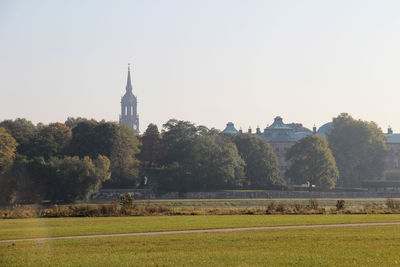 Trees and buildings against clear sky