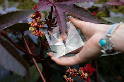 Cropped hand of woman holding pyramid crystal outdoors