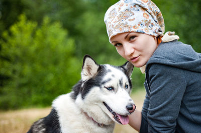 A young girl while walking in the park with a dog, hugging the dog husky and kissing.