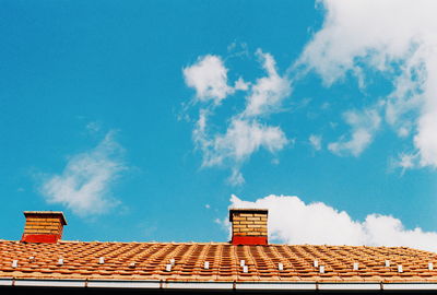 Low angle view of smoke stacks on roof against sky