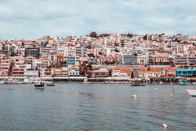 Aerial view of townscape by sea against sky