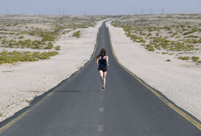 Rear view of man walking on road