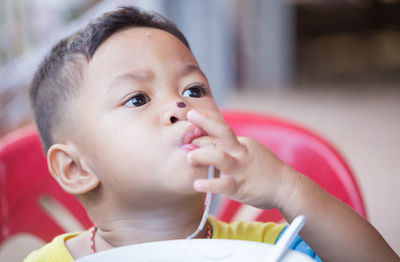 Close-up of cute boy with nose injury eating food while sitting at home