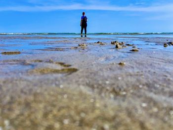 Full length of man walking on beach against sky
