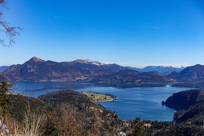 Scenic view of sea and mountains against clear blue sky