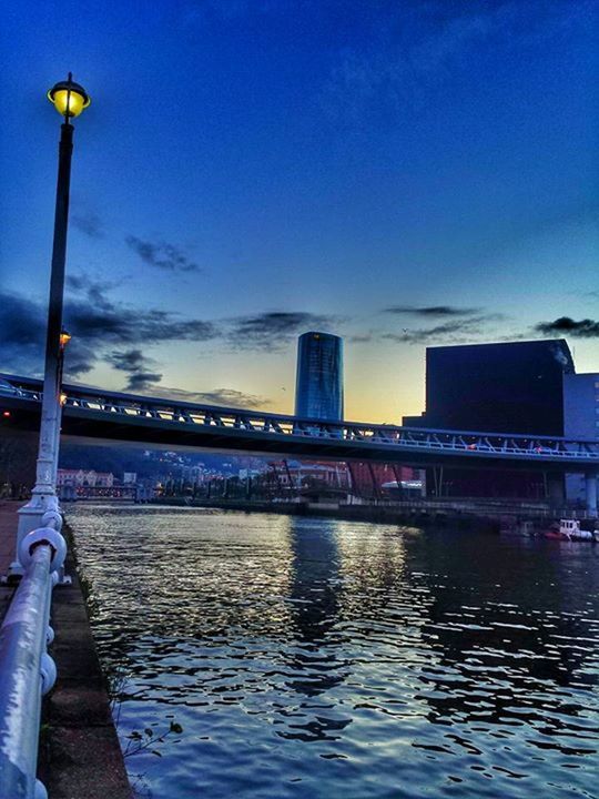 architecture, built structure, water, illuminated, sky, building exterior, blue, waterfront, transportation, street light, bridge - man made structure, city, river, dusk, reflection, connection, cloud - sky, sunset, outdoors, lighting equipment