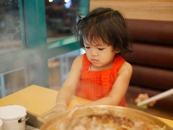 Girl looking away while sitting in restaurant