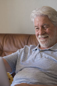 Portrait of senior man sitting on sofa at home
