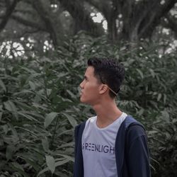 Young man looking away while standing on land