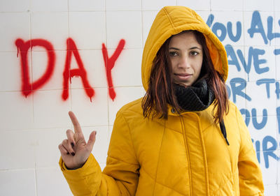 Portrait of young woman standing against wall