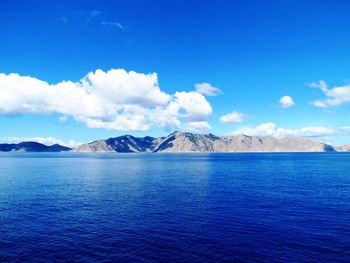 Scenic view of sea and mountains against blue sky