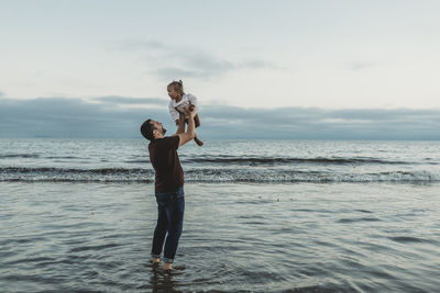 Dad throwing his daughter in air in the ocean