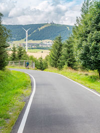 Road amidst trees and plants against sky