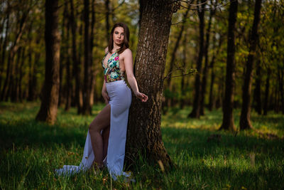 Portrait of woman standing on tree trunk in forest