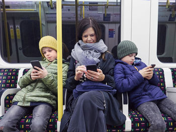 Mother and son using cell phones in subway train