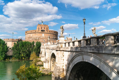 Arch bridge over river against cloudy sky