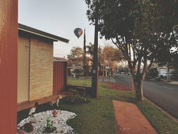 Street amidst trees and buildings against sky