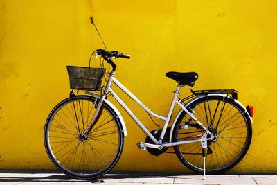 Bicycle parked against yellow wall