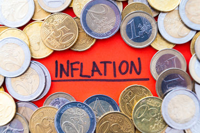 Word inflation, on red paper, surrounded by euro coins. rising prices, economic repercussions.