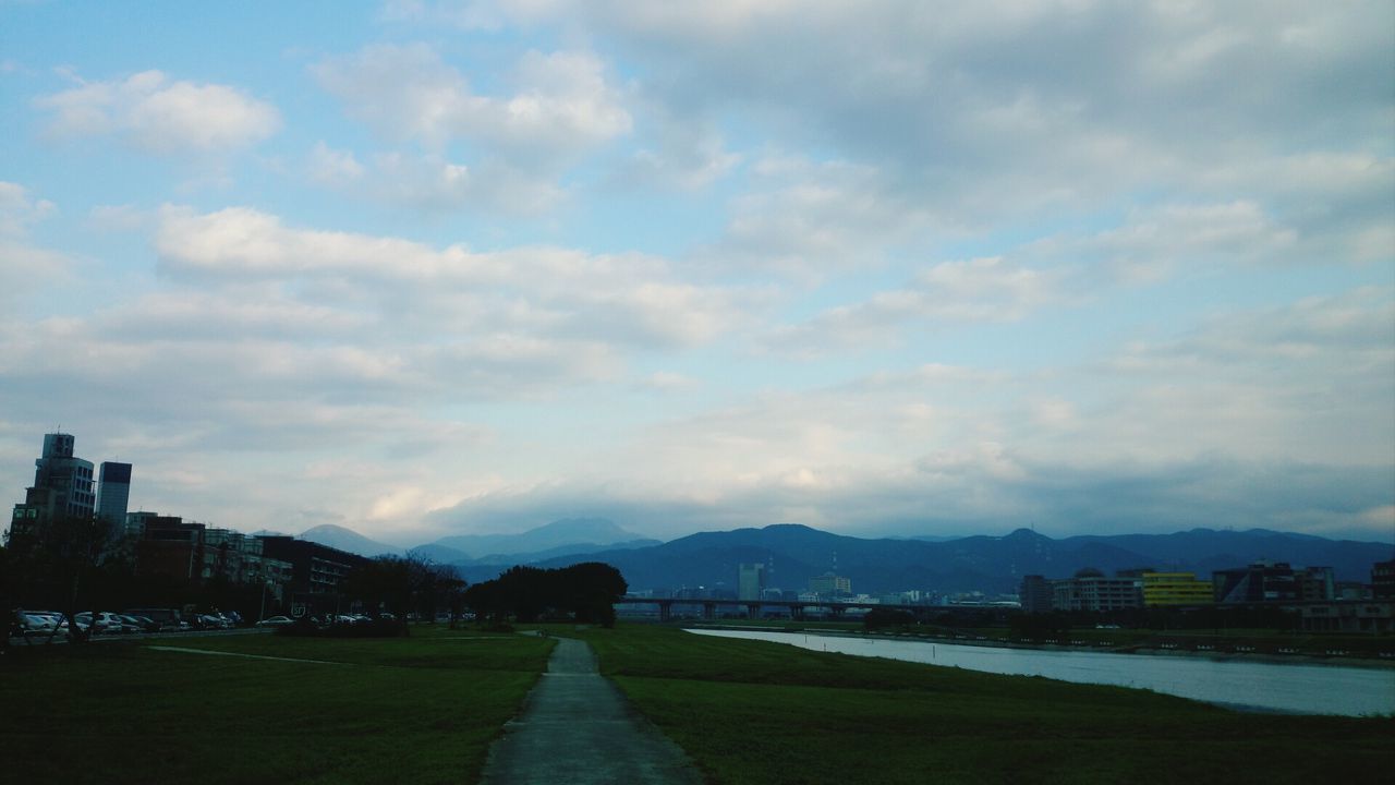 sky, the way forward, water, cloud - sky, built structure, architecture, building exterior, road, river, transportation, cloudy, cloud, mountain, diminishing perspective, city, nature, vanishing point, street, outdoors, scenics