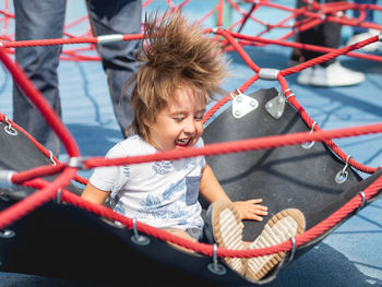 Laughing toddler is jumping on playground.outdoor sport equipment for children physical development.