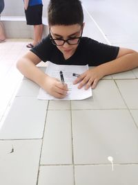 High angle view of boy writing on paper in school