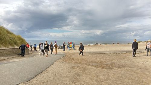 People walking on beach against sky