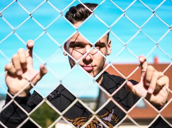 Portrait of man holding chainlink fence