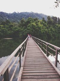 Footbridge over stream against trees and mountains