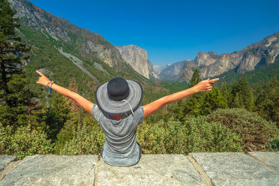 Rear view of person with arms raised against mountains