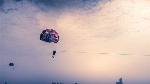 Low angle view of people flying kite against sky