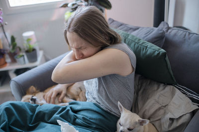 Woman coughing in her arm