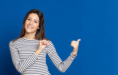 Portrait of young woman standing against blue background