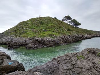 Scenic view of rocks by sea against sky