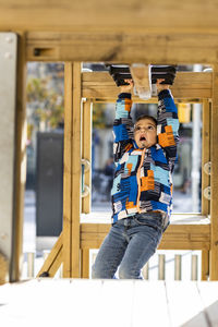 Boy hanging from monkey bars at playground 