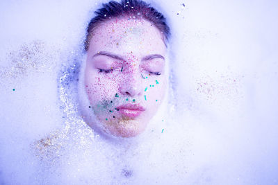 Close-up of young woman with eyes closed and glittered face in bathroom