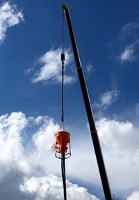 Low angle view of crane against cloudy sky