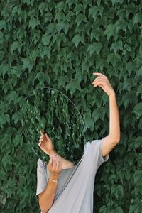 Man holding mirror while standing by plants