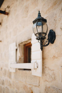 Low angle view of lamp mounted on wall of old building