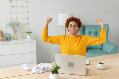 Portrait of smiling woman using mobile phone while standing in office