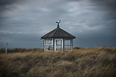 Lifeguard hut on landscape against sky