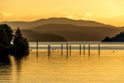 High angle view of wooden posts in river against silhouette mountains