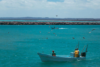 People in sea against sky