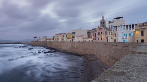 Buildings on beach against cloudy sky