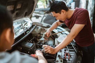 Side view of young man repairing car