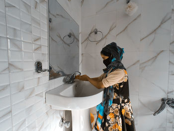 Rear view of woman working in bathroom at home